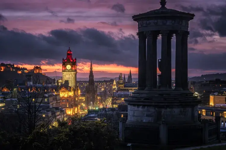 Edinburgh city skyline at dusk, with the monument on Calton Hill in the foreground.
